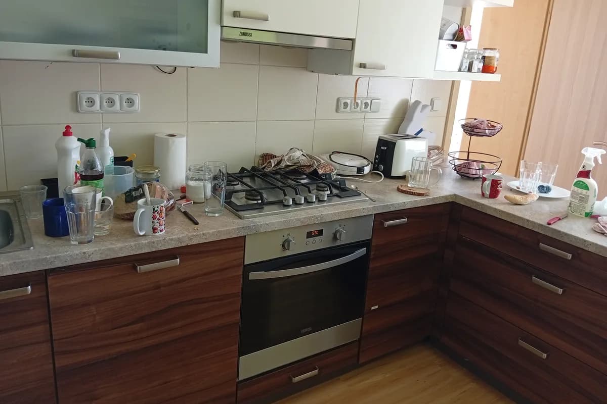 Kuchyňská linka před úklidem – věci a nádobí rozložené po desce